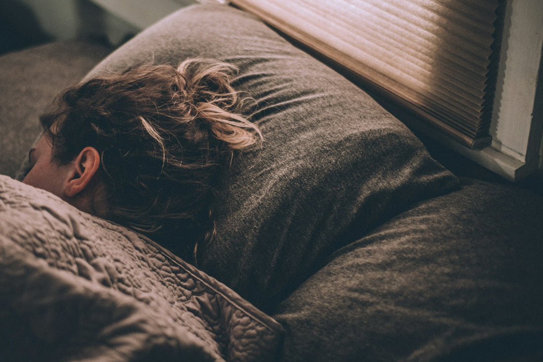 Mujer descansando plácidamente en la cama con luz natural suave